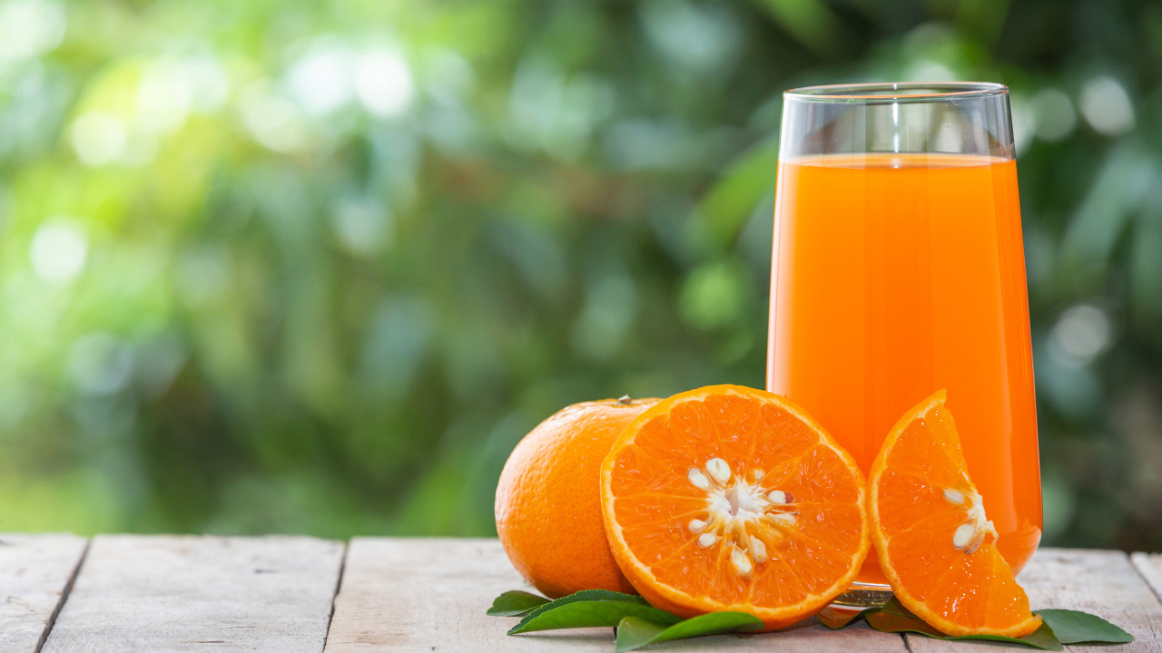 Стакан сока с апельсинами на деревянном столе