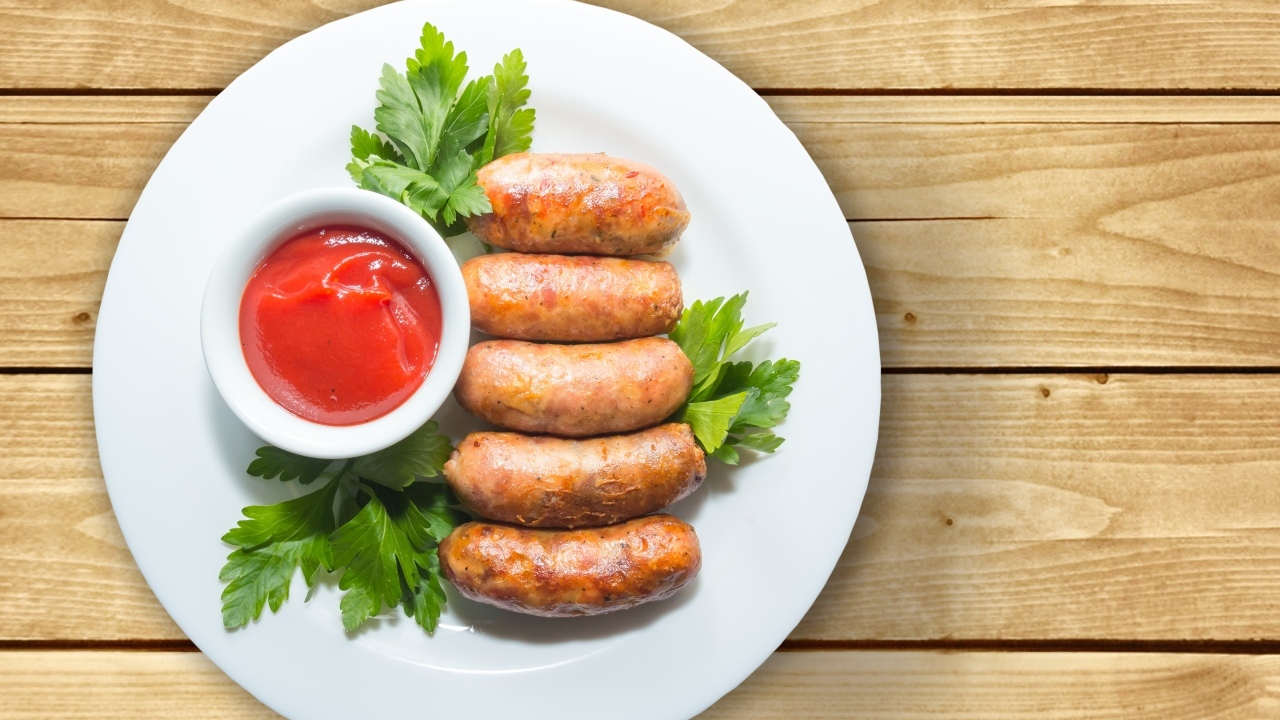 Сардельки на тарелке с соусом и петрушкой