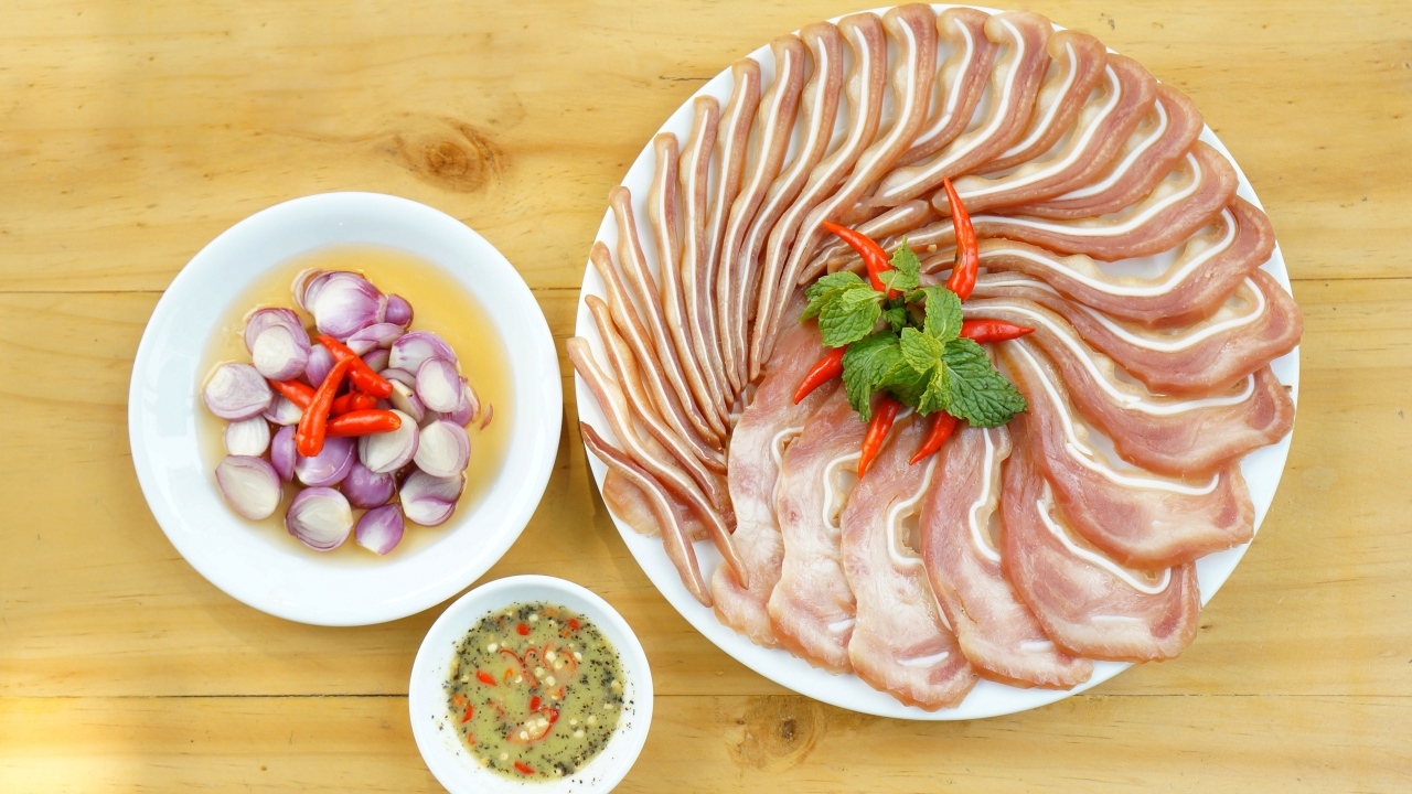 Копченые свиные уши на столе с луком и соусом