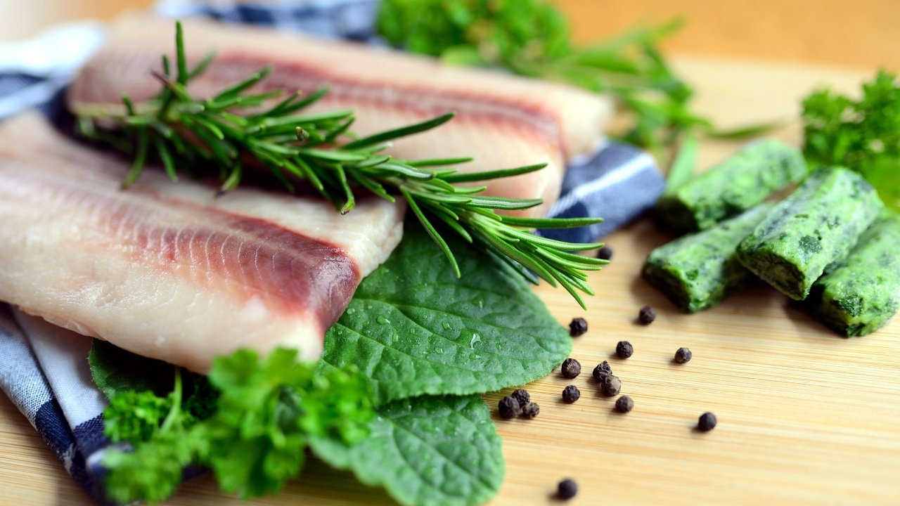 Свежая рыба на доске с зеленью и специями