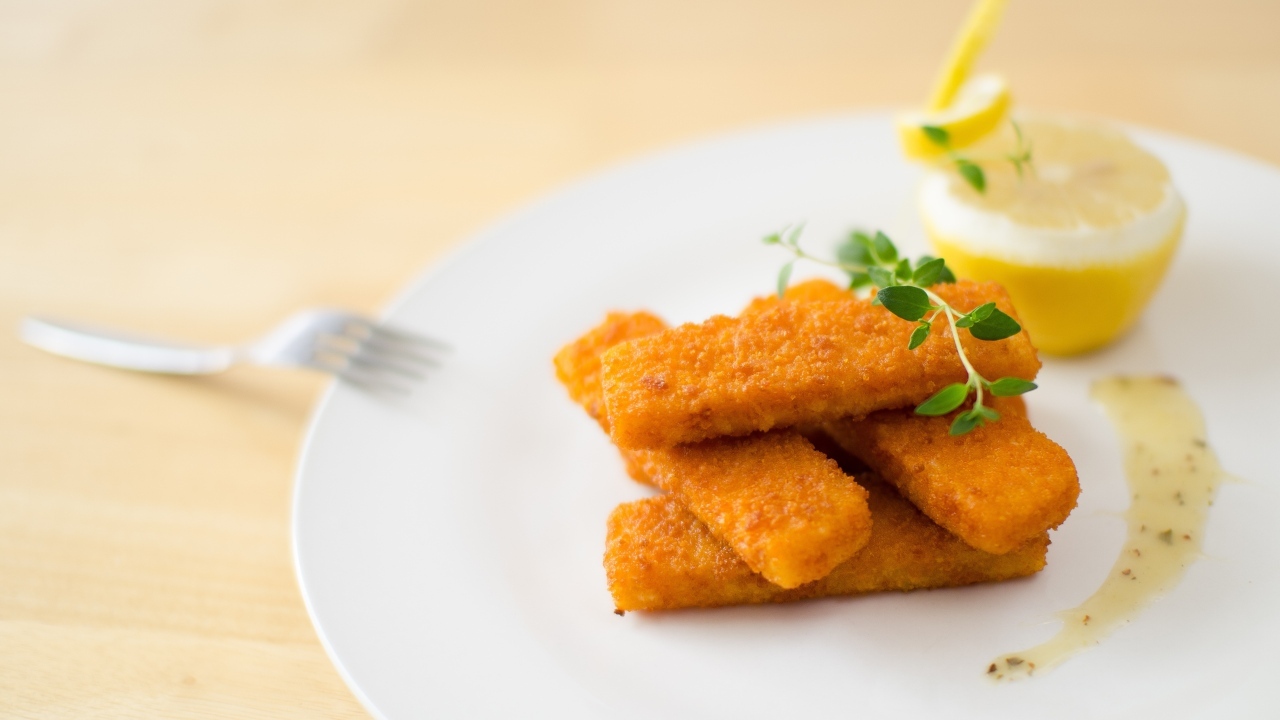 Жареные рыбные палочки на тарелке с лимоном