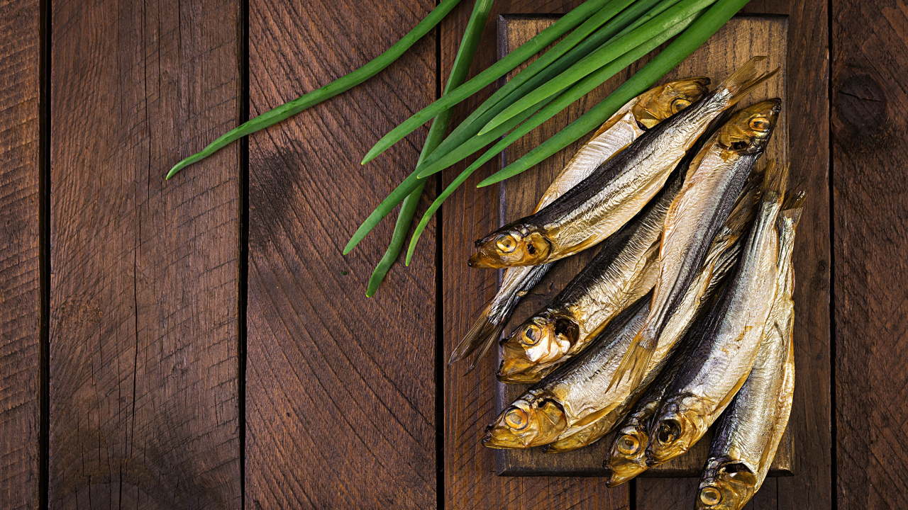 Рыба салака на столе с зеленым луком