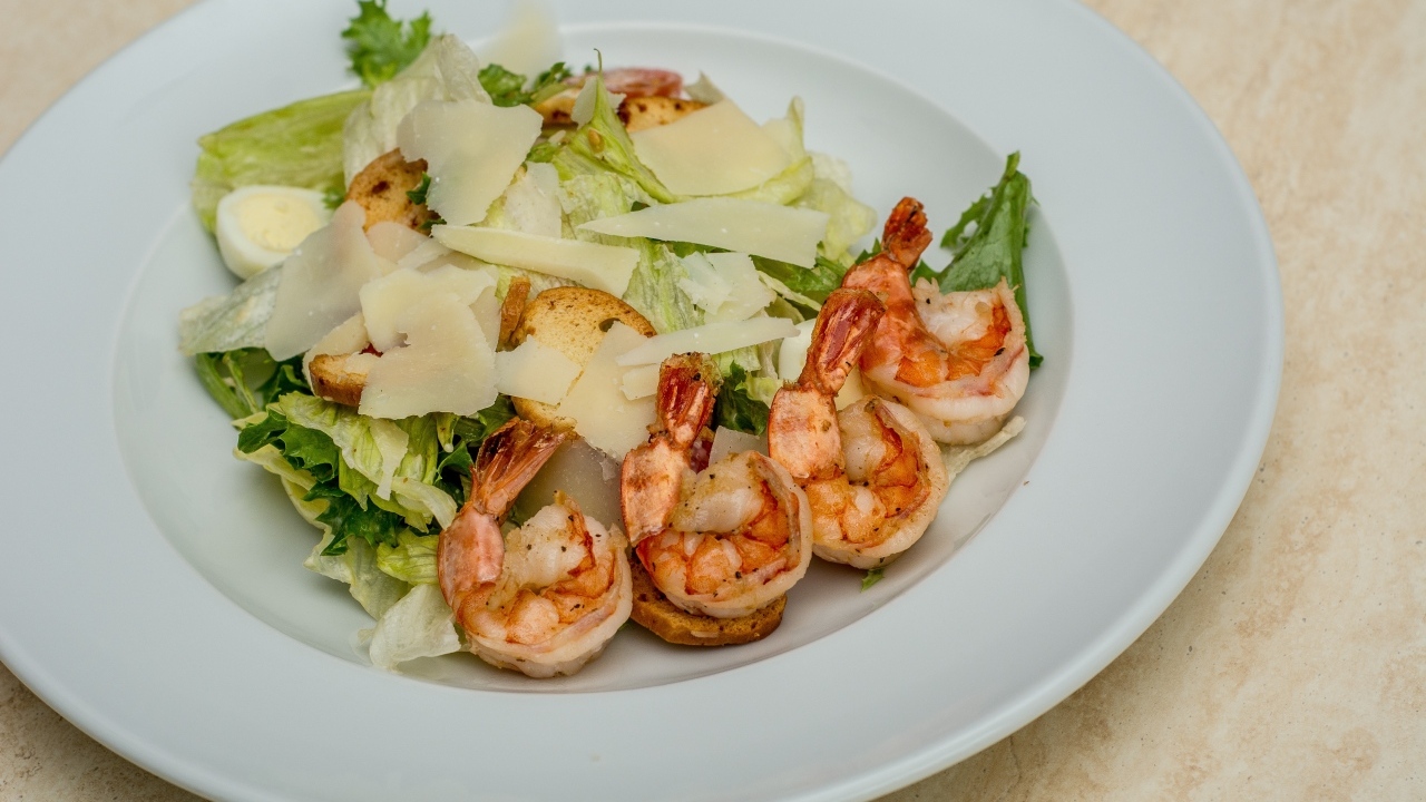 Креветки на тарелке с листьями салата