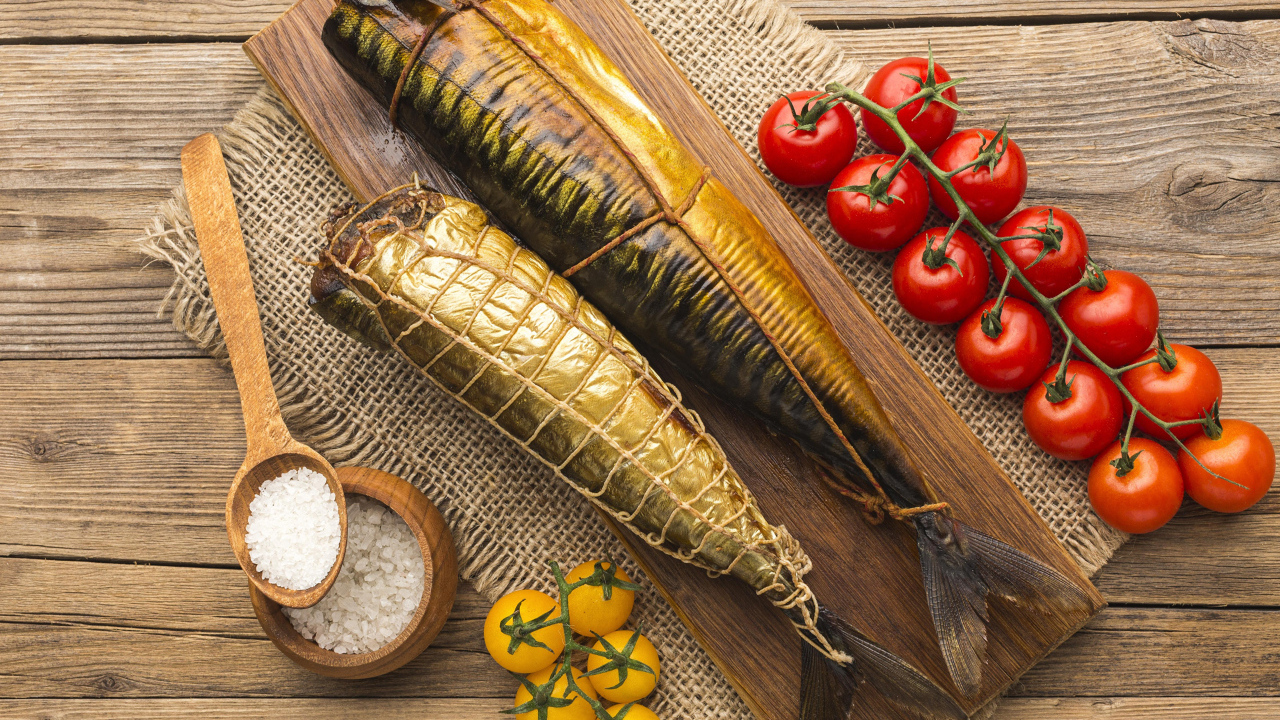 Две копченые скумбрии на столе с помидорами