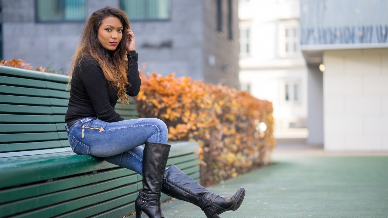 Брюнетка в синих джинсах сидит на лавке
