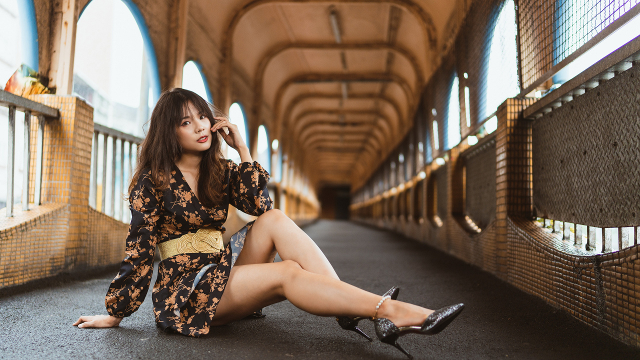 Девушка в красивом коротком платье сидит на полу