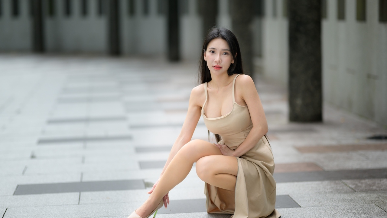 Девушка азиатка в платье сидит на корточках