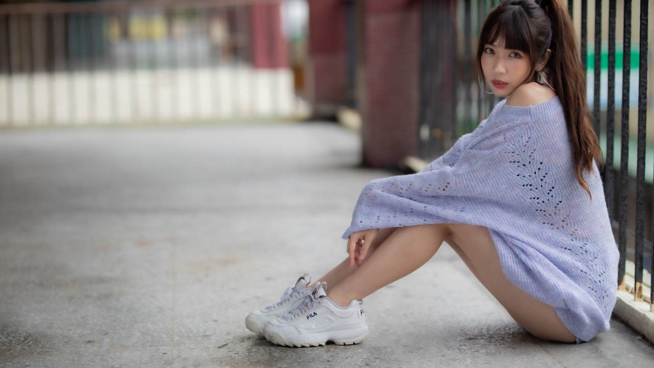Девушка азиатка в свитере и белых кроссовках 