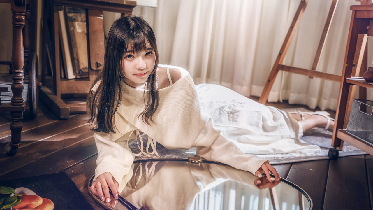 Девушка азиатка в белом платье лежит на полу