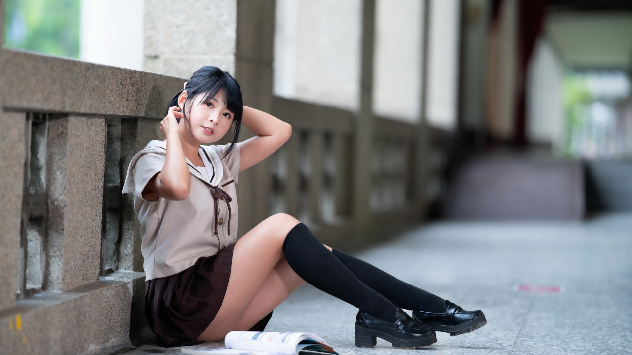 Девушка азиатка в школьной форме сидит на полу