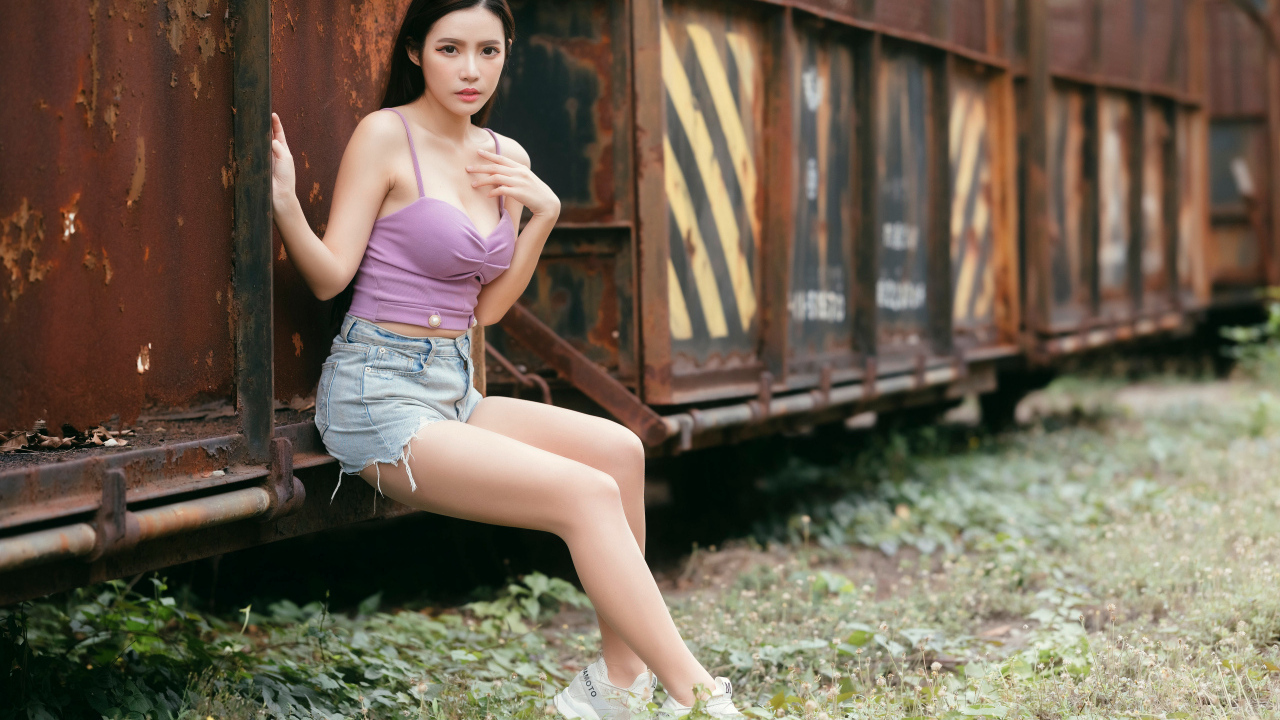 Девушка азиатка сидит у ржавого вагона