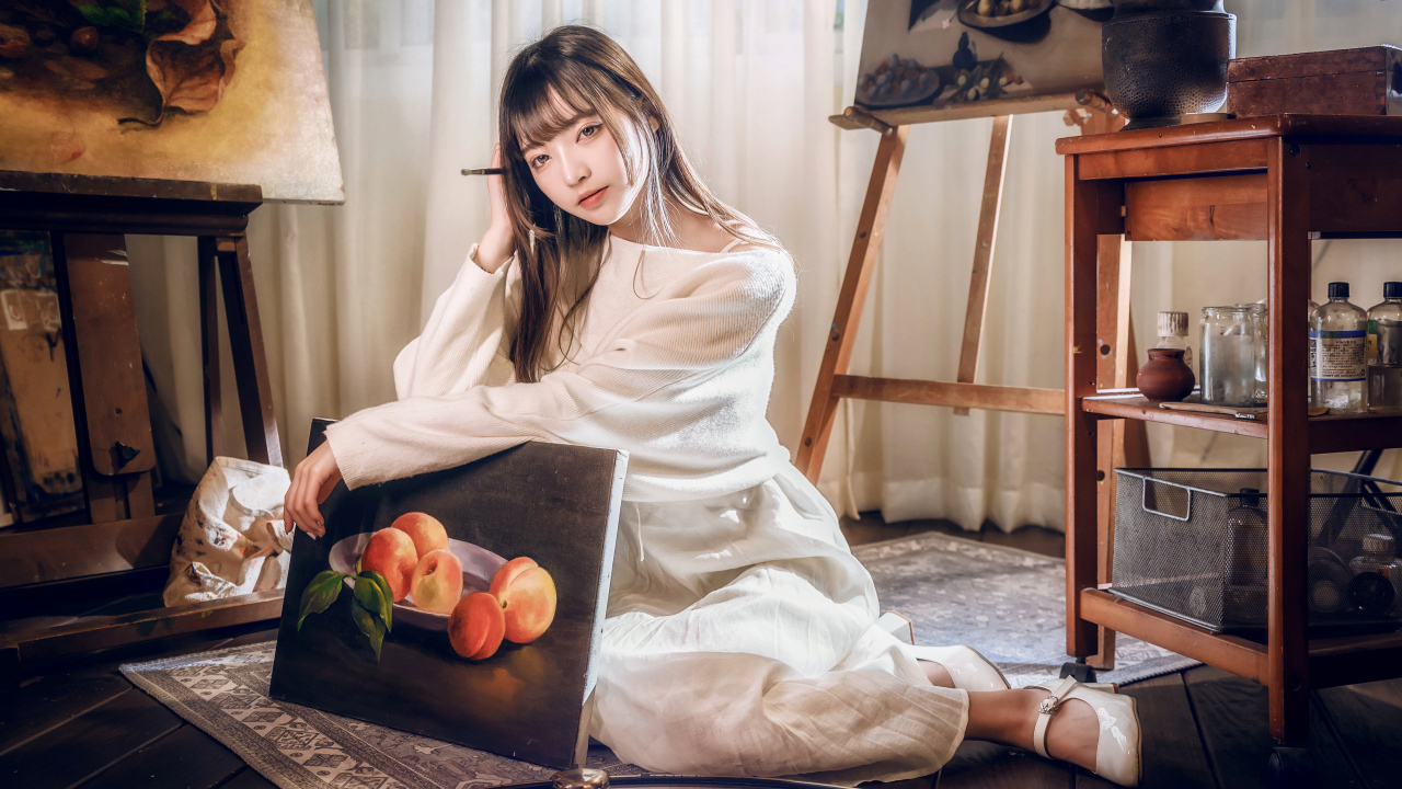 Девушка азиатка сидит с картиной на полу