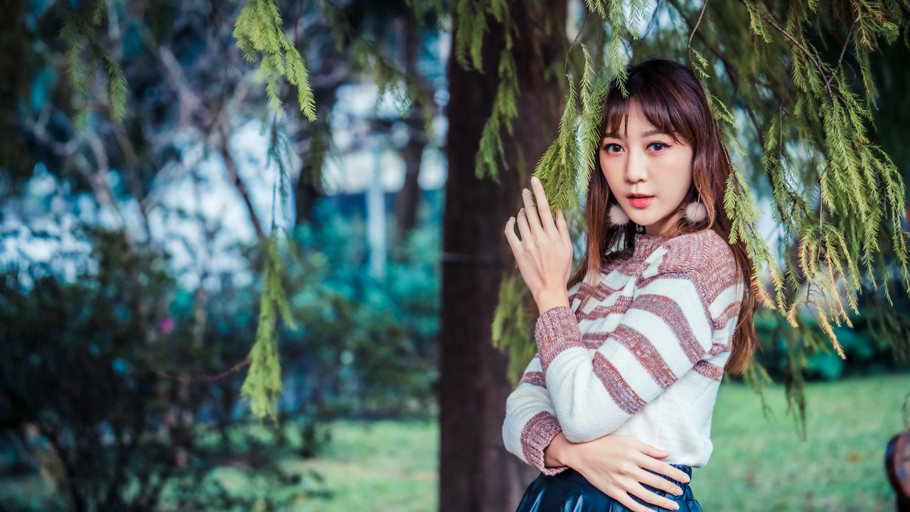 Девушка азиатка стоит у дерева ели