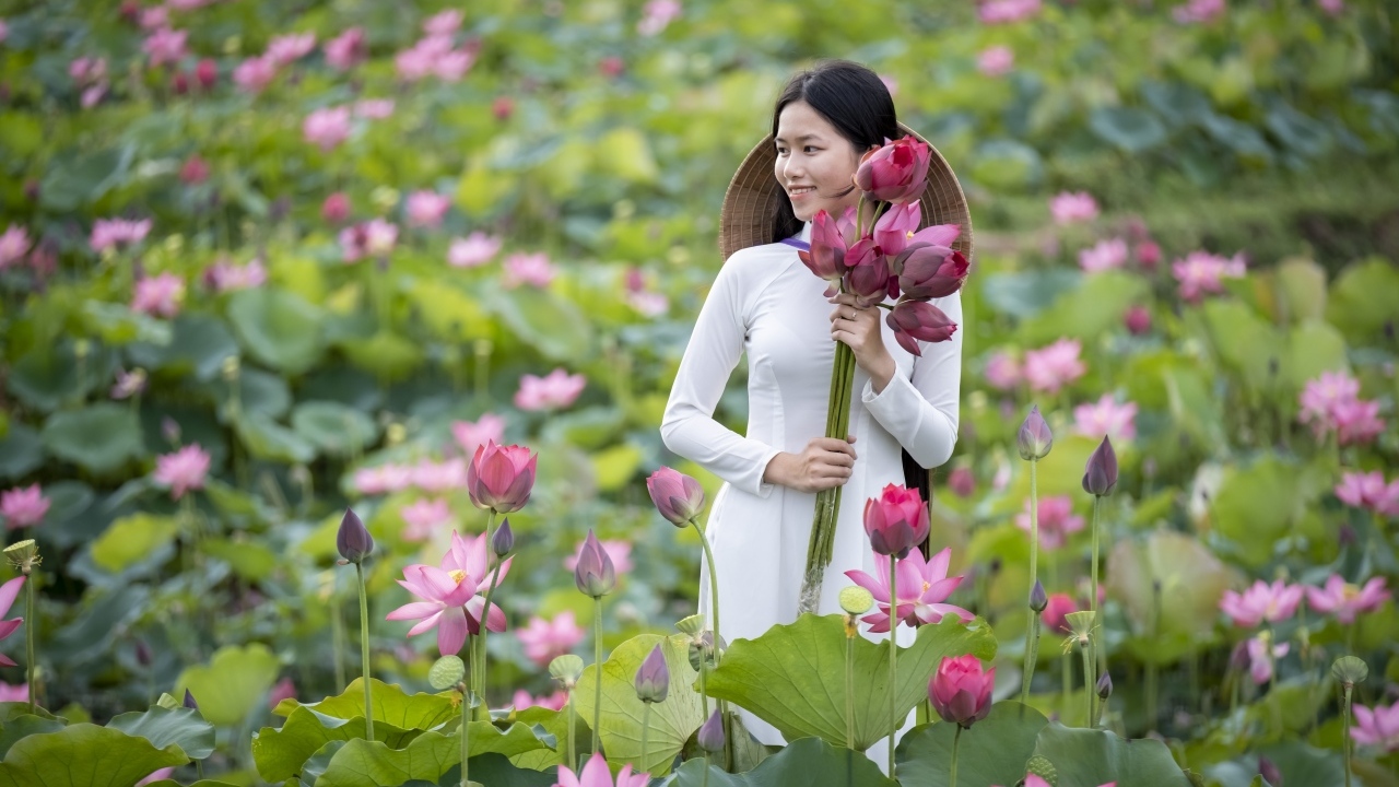 Девушка азиатка с розовыми цветами лотоса в руках