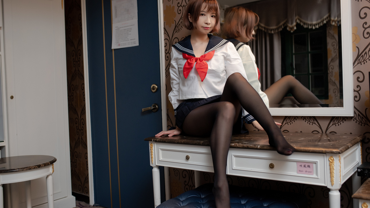 Азиатка в форме сидит на столе