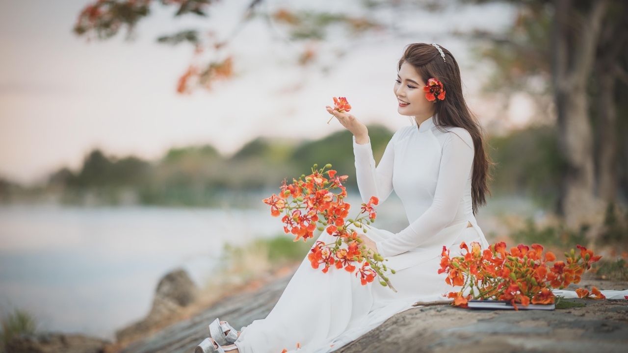 Красивая девушка азиатка в белом платье с цветами в руке