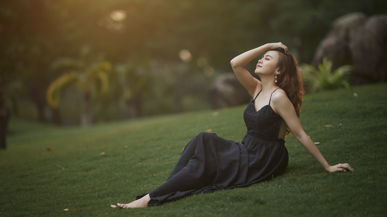 Красивая азиатка с закрытыми глазами в черном платье