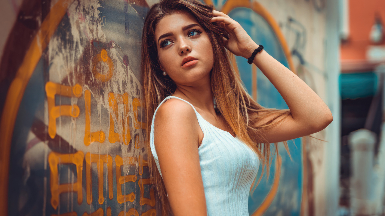 Красивая голубоглазая девушка стоит у стены