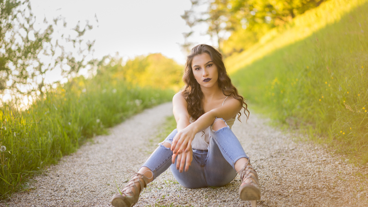 Красивая девушка сидит на дороге летом