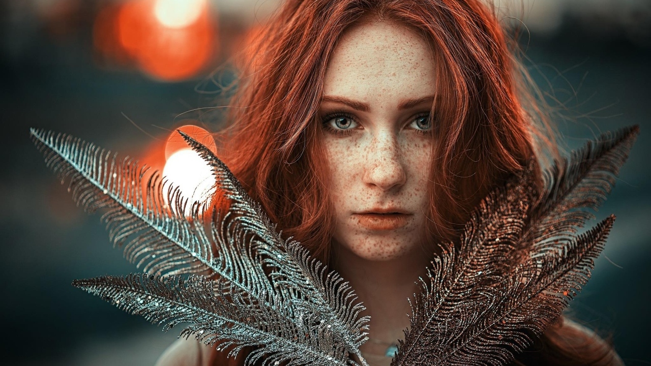 Яркая рыжеволосая девушка с перьями в руках