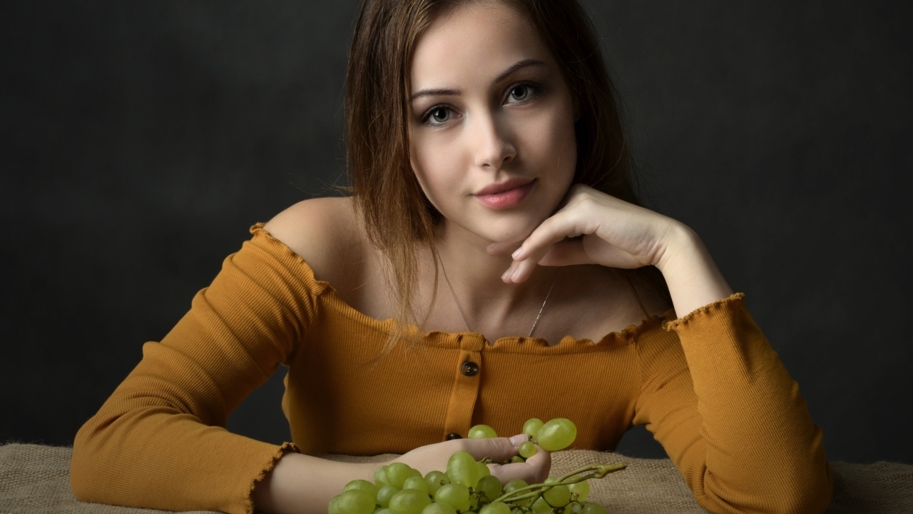 Милая шатенка ест белый виноград