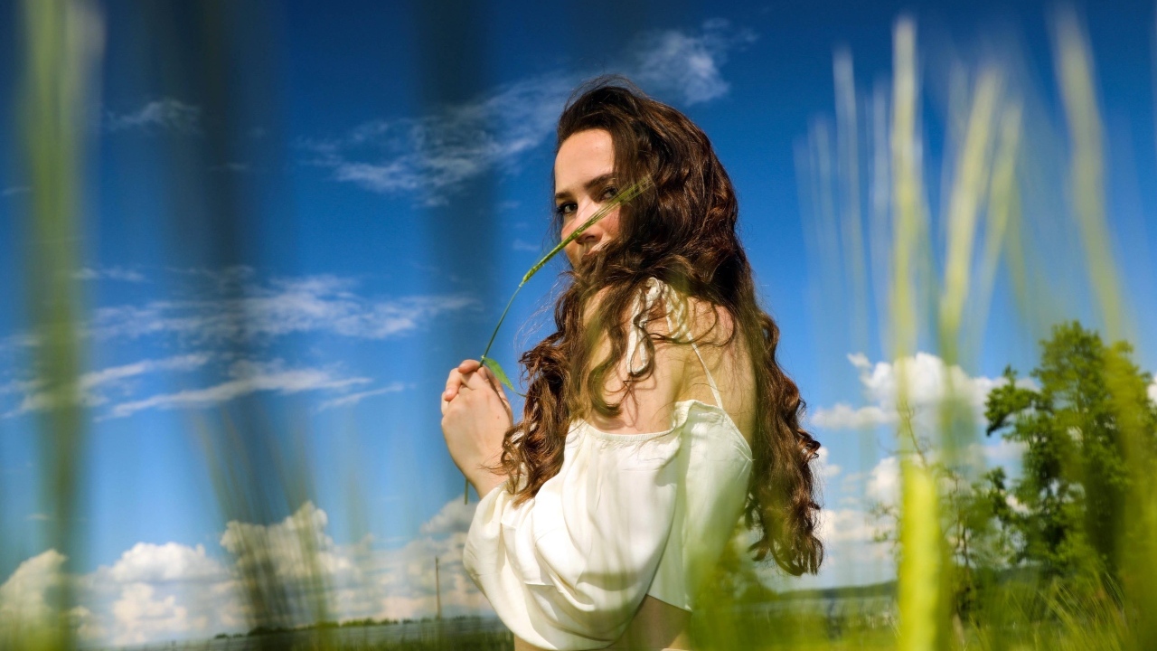 Милая девушка на поле на фоне голубого неба