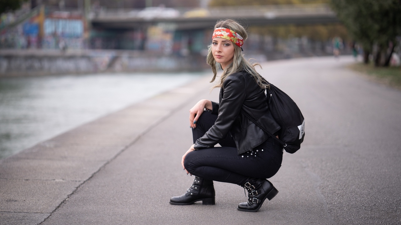 Девушка в черном костюме сидит на корточках