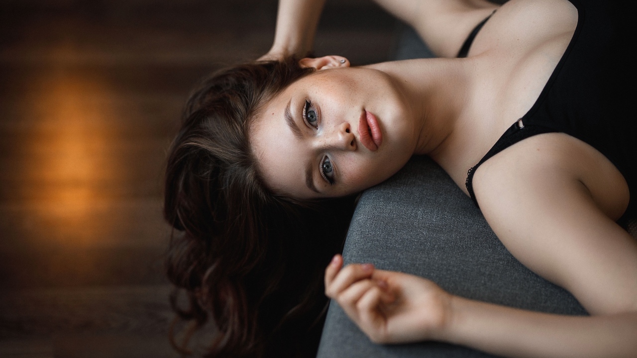 Девушка с длинными волосами лежит  на кровати