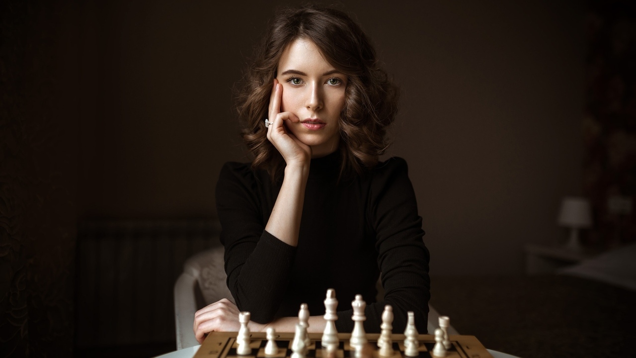 Умная молодая девушка играет в шахматы