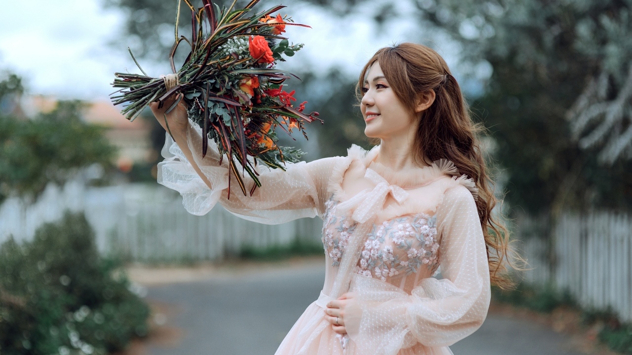 Улыбающаяся девушка азиатка в розовом платье с букетом