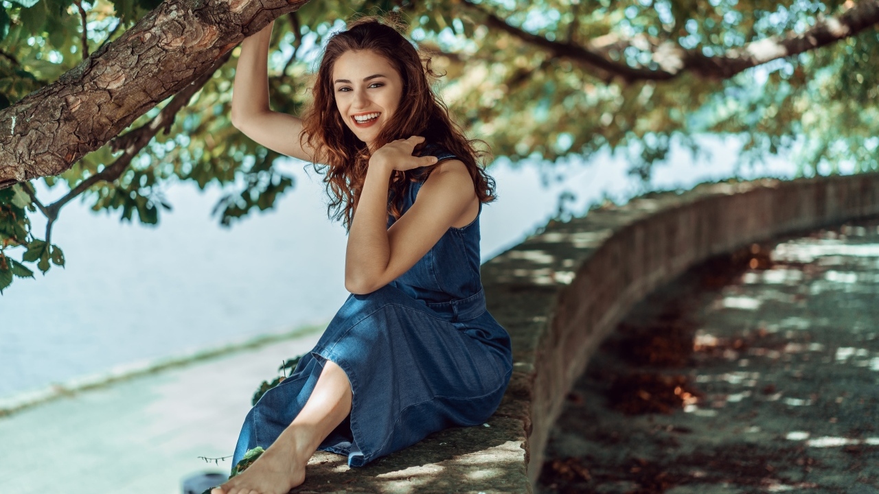 Улыбающаяся девушки сидит у дерева