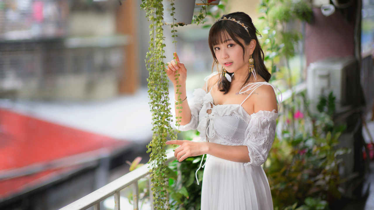 Молодая азиатка в белом платье у растений