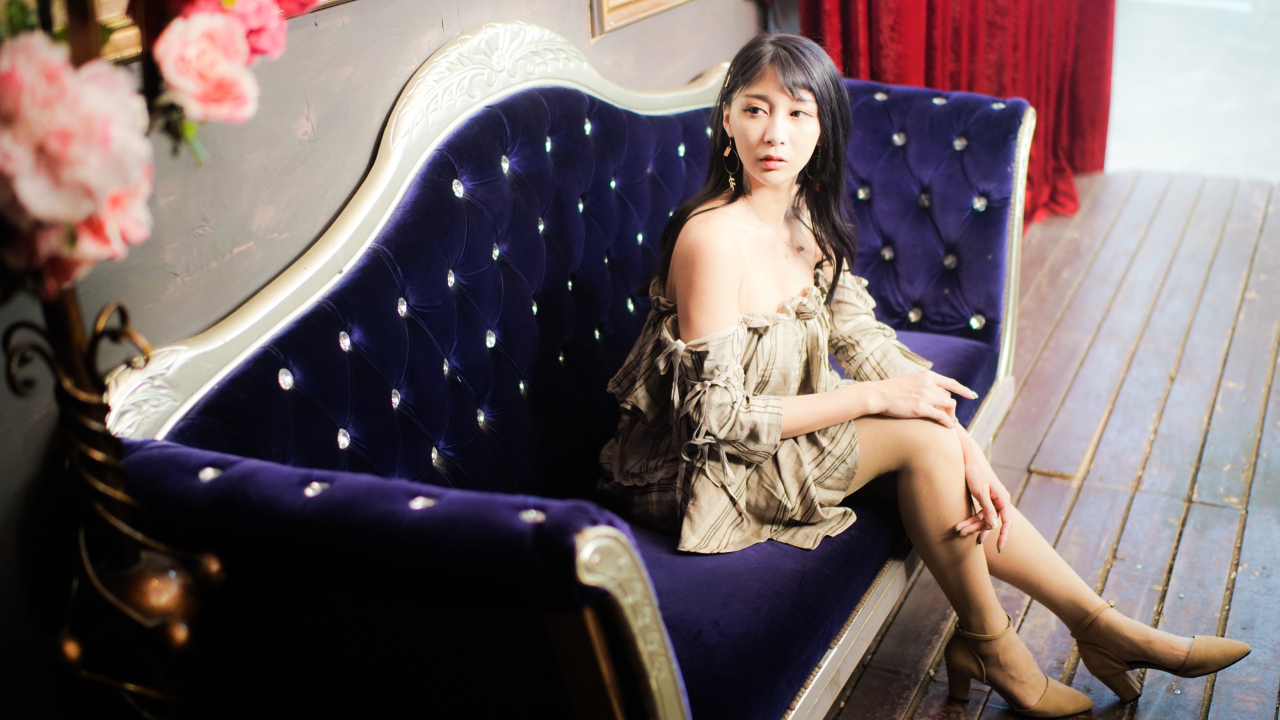 Молодая азиатка сидит на красивом диване