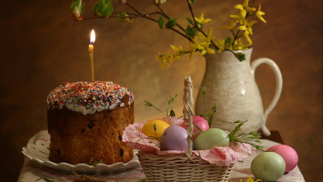 Кулич со свечой и крашеными яйцами на столе на Пасху