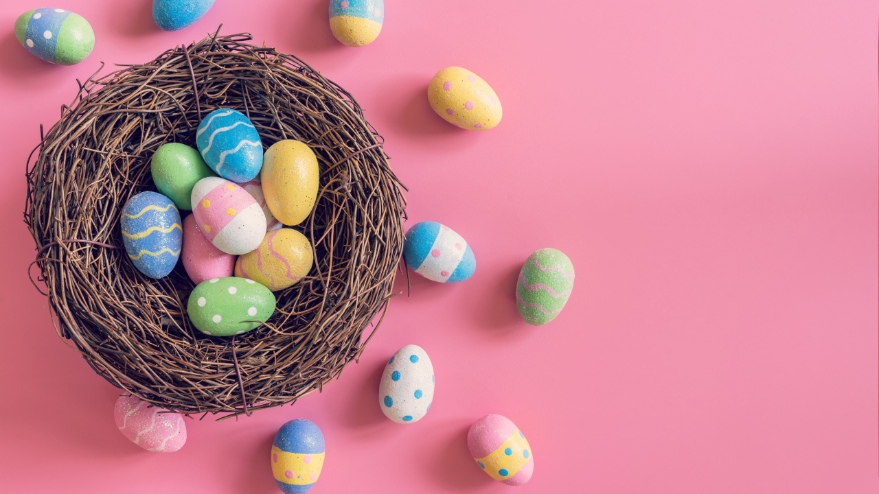 Гнездо с разноцветными яйцами на розовом фоне на Пасху