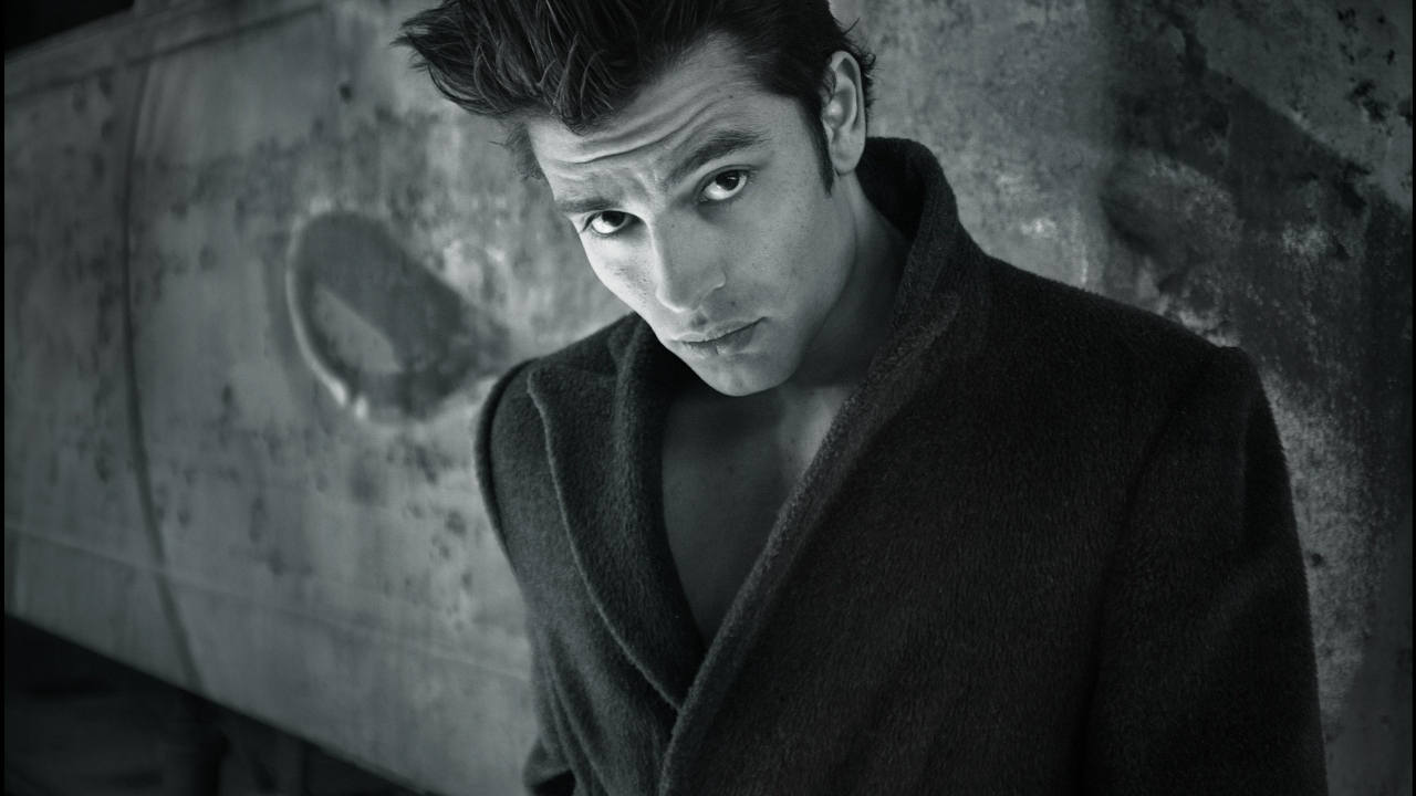 Красивый мужчина в черном пальто у стены