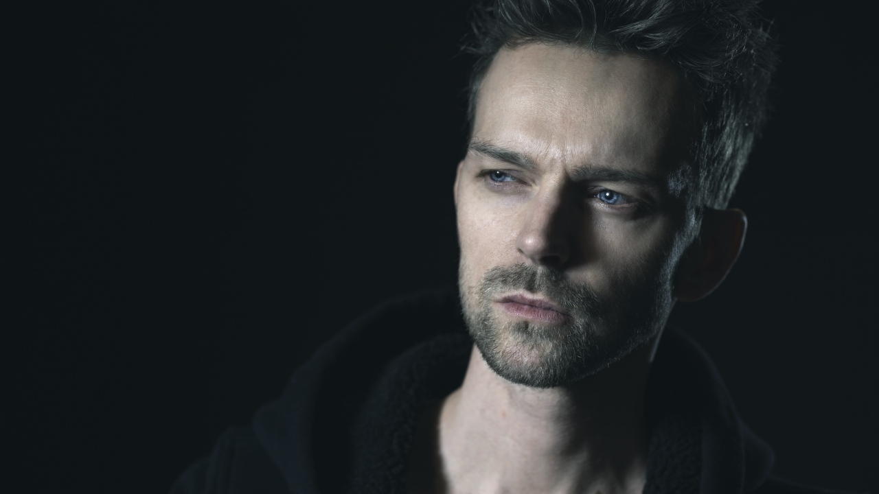 Серьезный голубоглазый мужчина на черном фоне