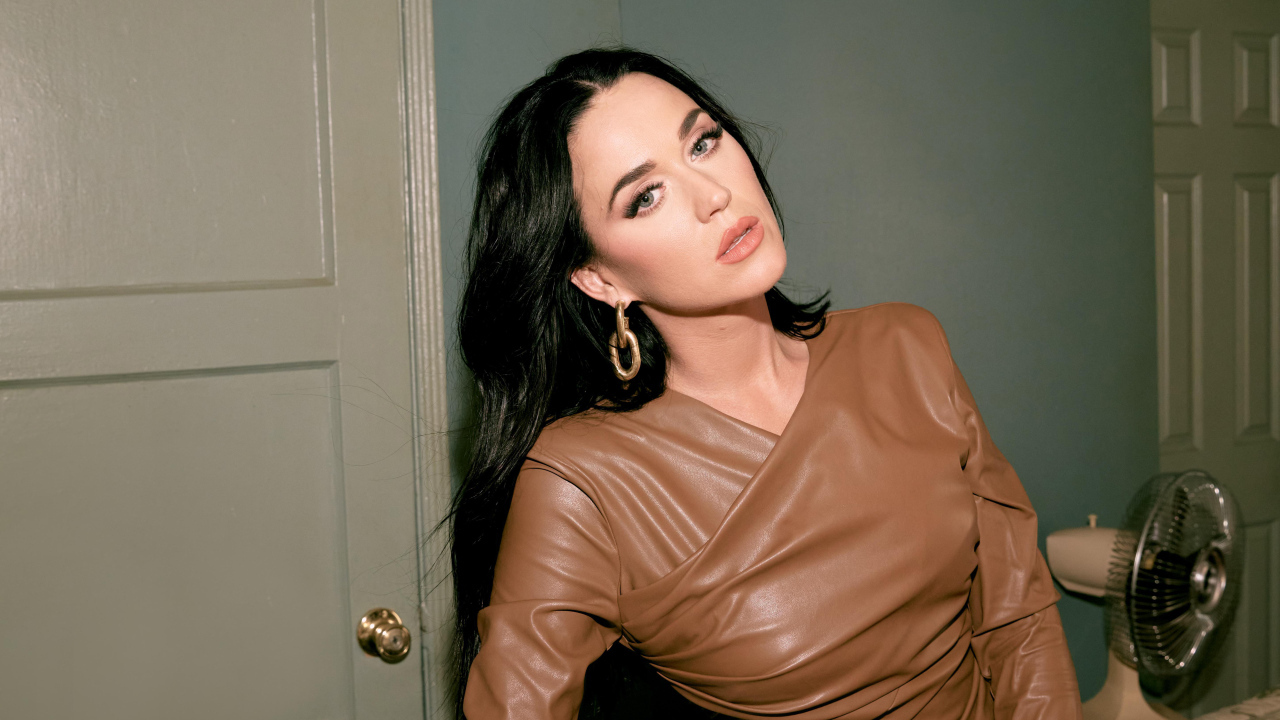 Длинноволосая брюнетка Кэти Перри стоит в комнате у двери