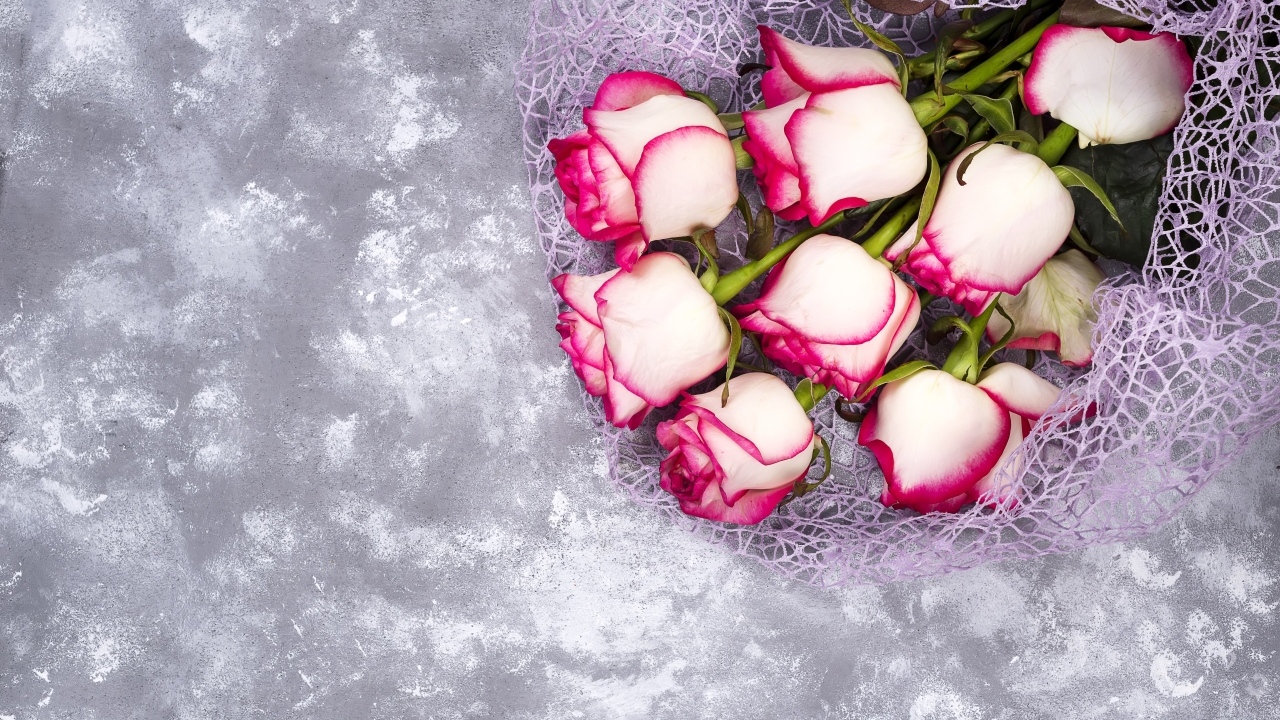 Красивый букет роз в упаковке на сером столе