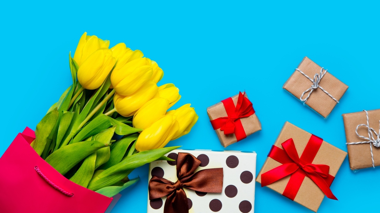 Букет желтых тюльпанов с подарками на голубом фоне