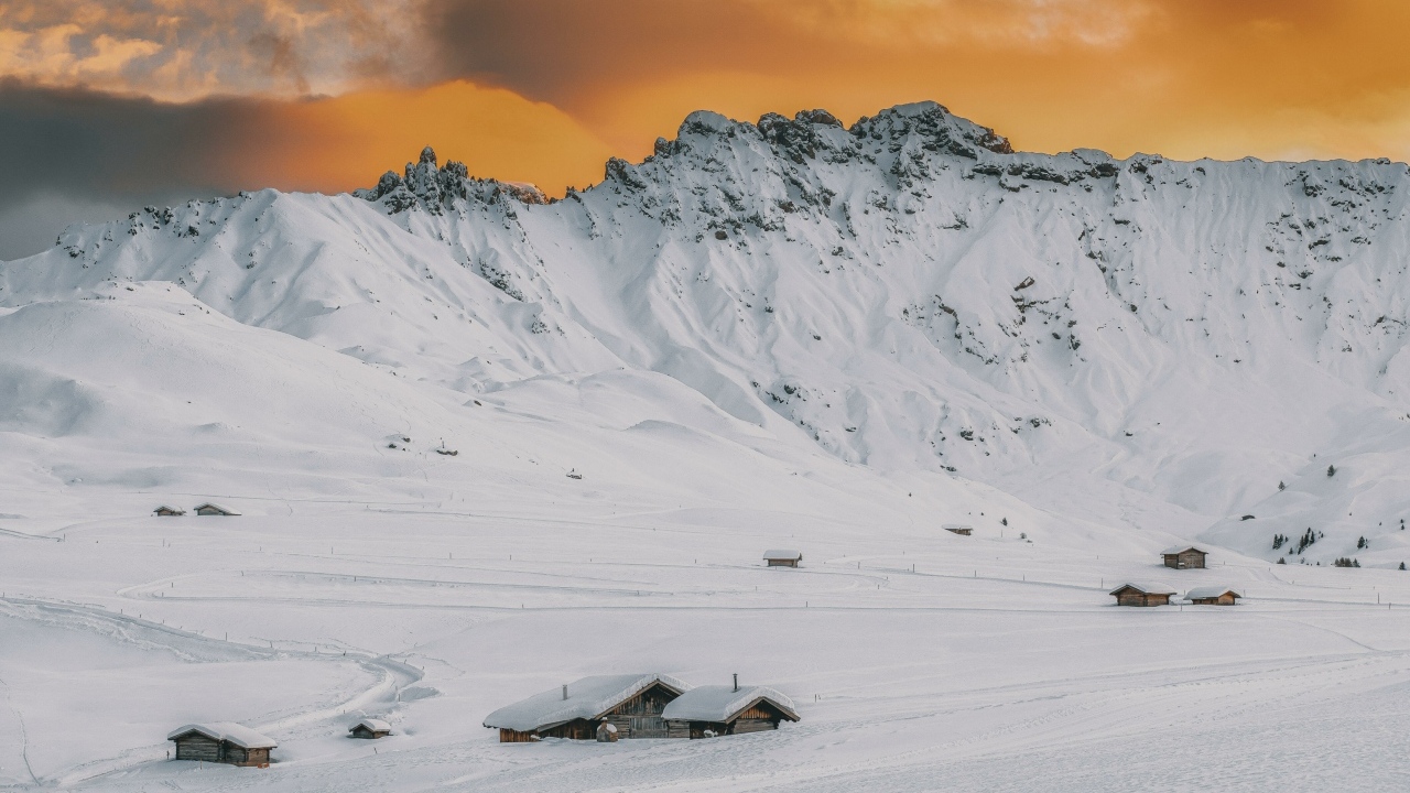 Красивая заснеженная гора под оранжевым небом