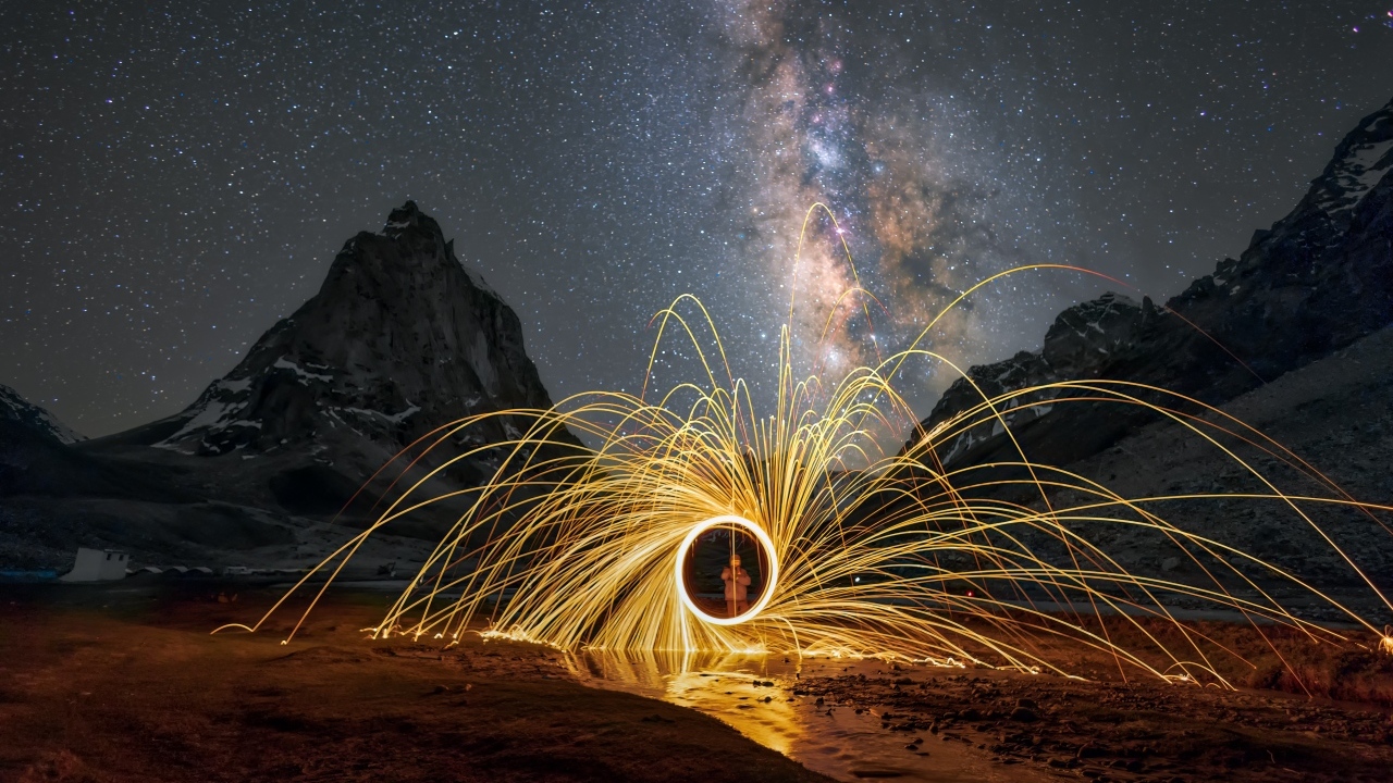 Огненное шоу под ночным красивым небом в горах