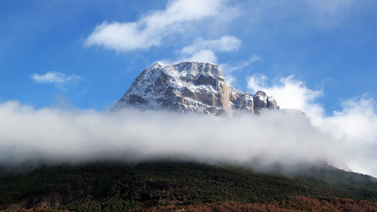 Заснеженная горная вершина в белых облаках