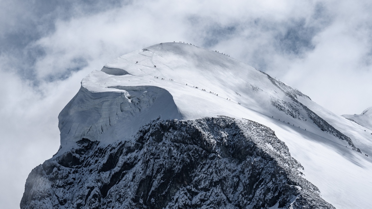 Вид на заснеженную вершину горы под белыми облаками