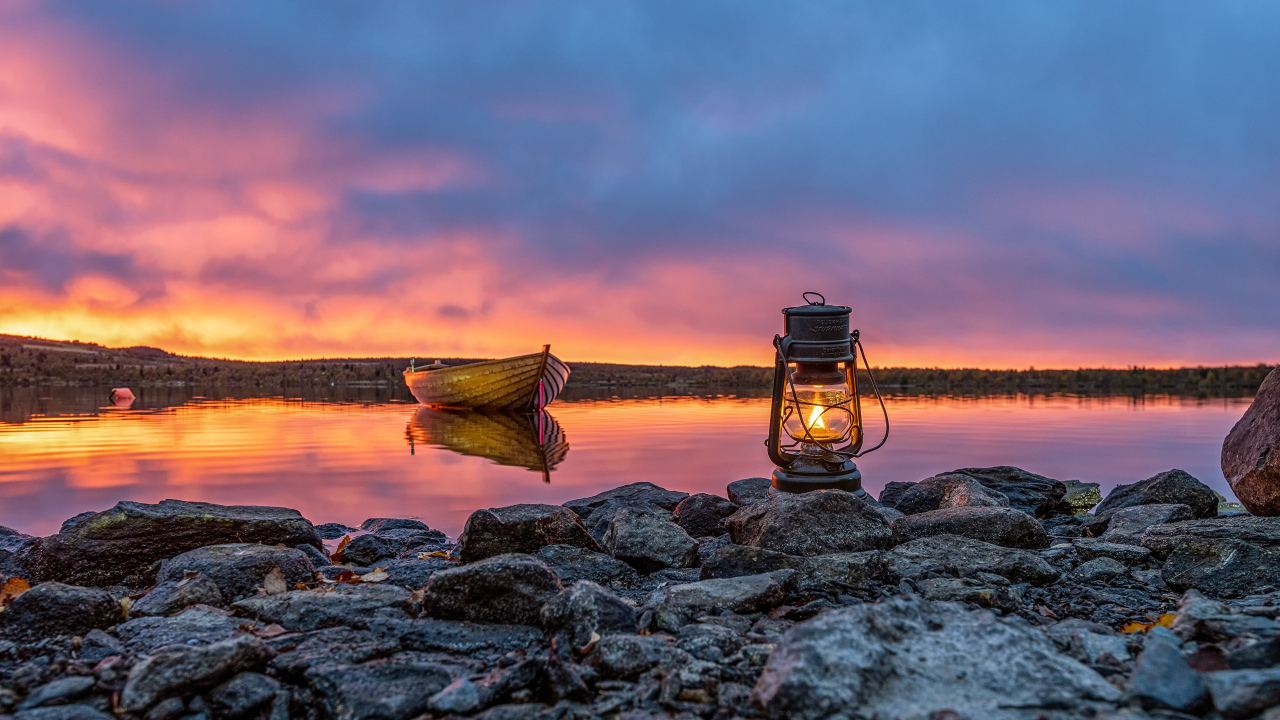 Керосиновая лампа стоит на камнях у озера