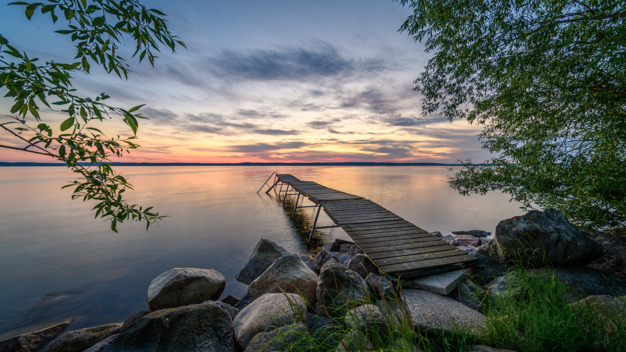 Старый деревянный пирс у озера на закате