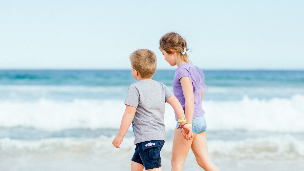 Мальчик и девочка идут по песку у моря