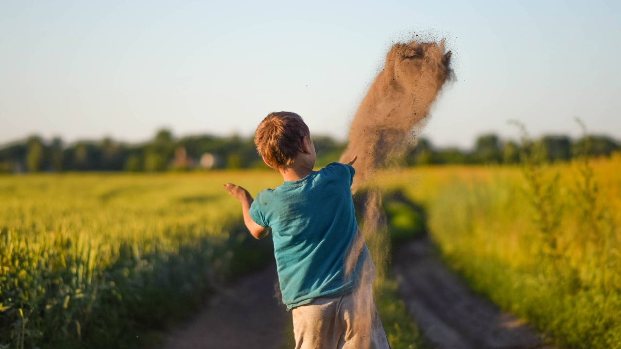 Мальчик бросает песок на дороге