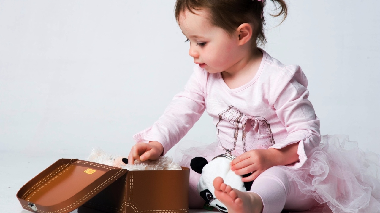 Девочка в розовом наряде с маленьким чемоданом