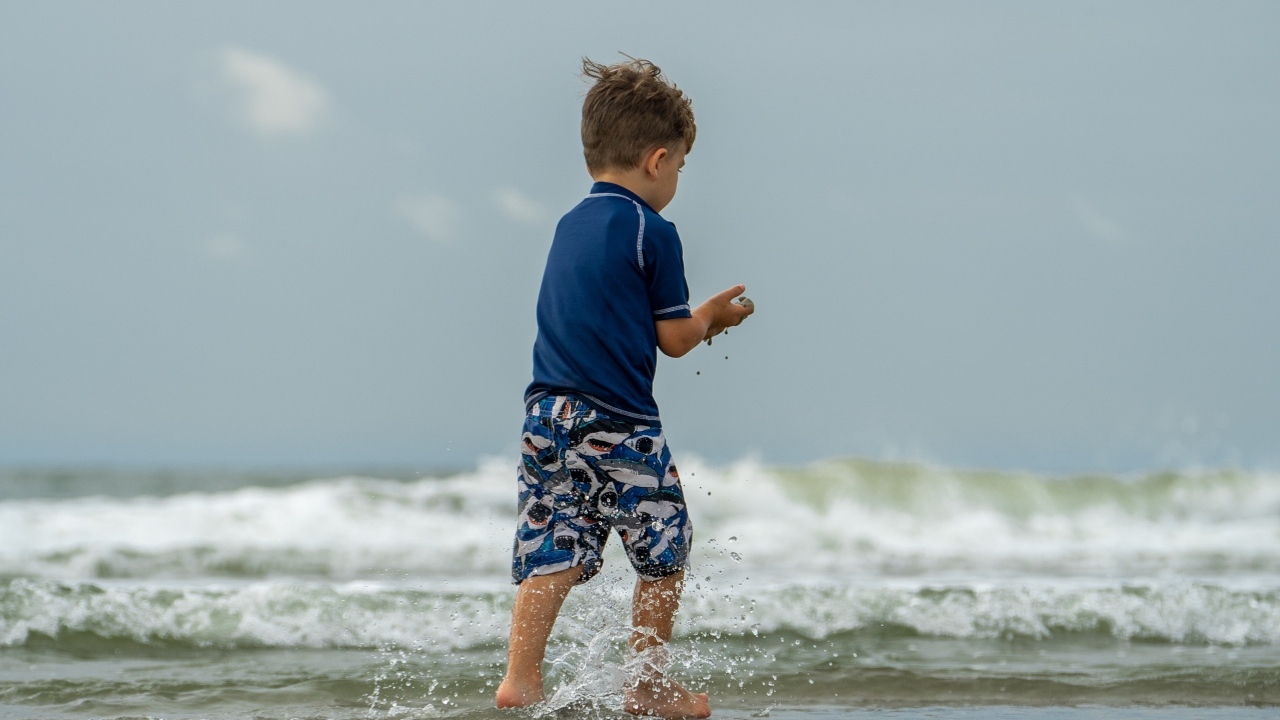 Маленький мальчик гуляет по морскому берегу